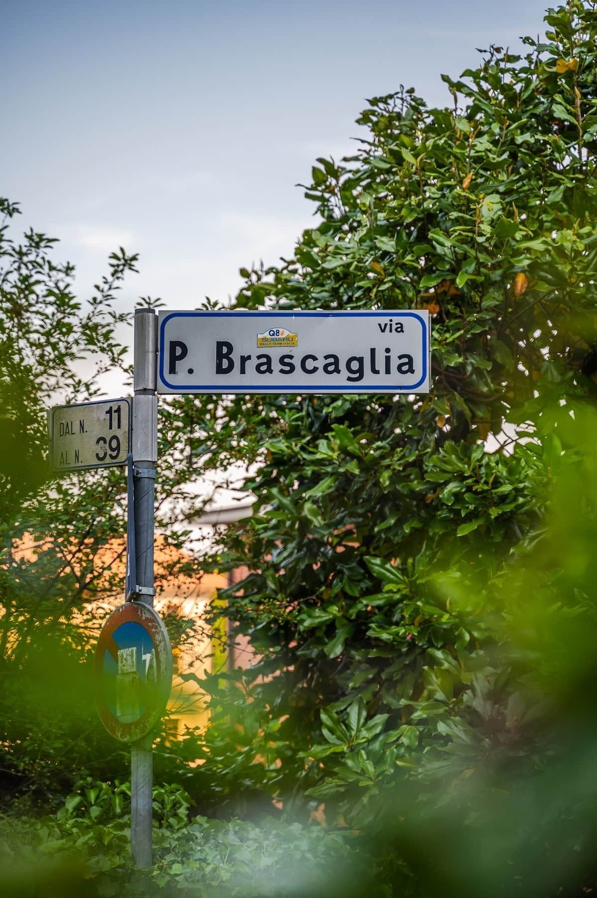 A street sign for 'P. Brascaglia' with a nearby directional sign indicating 'DAL N. 11' and 'AL N. 39'.
