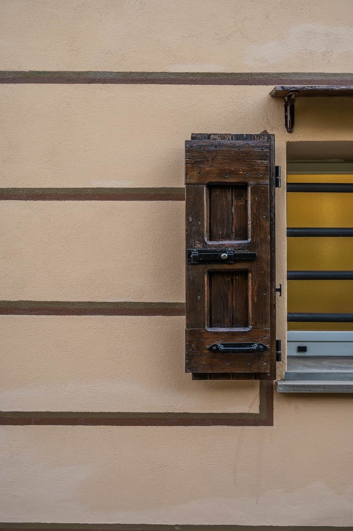 A building facade with a wooden shuttered window and a metal shutter.