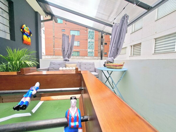 A rooftop terrace with a foosball table, a small table with a basket, and a sofa.