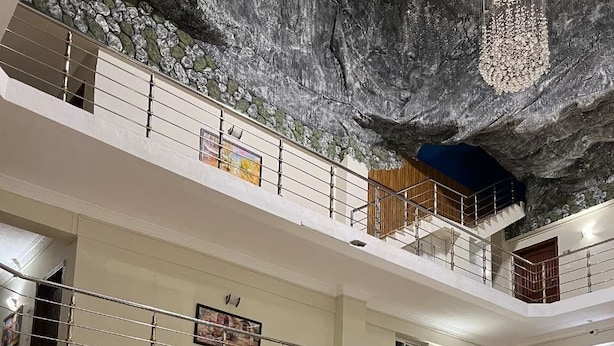 Eine mehrstöckige Hotelhalle mit roten Sofas, einem großen gemusterten Teppich und einer Wandverzierung.