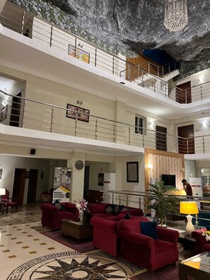 A multi-level hotel lobby with red sofas, a large patterned rug, and a decorative wall. - Holiday Grand Resort (Bhurban)
