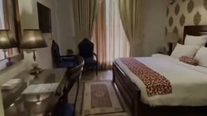 Ein Hotelzimmer mit Bett, Schreibtisch, Stuhl, Fernseher und Vorhängen.