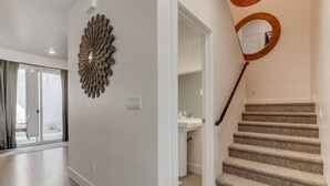 A modern interior with a staircase, a decorative wall piece, and a view to the outside. - The Lofts #17 Townhome Pool Resort, Poolside and Hot tub (St. George)