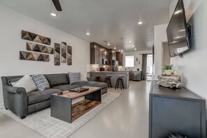 A modern living room with a grey sofa, a coffee table, and a TV mounted on the wall. - The Lofts #17 Townhome Pool Resort, Poolside and Hot tub (St. George)