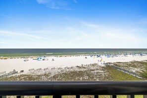 A beach with umbrellas and beach chairs, a sandy shore, and a clear sky.