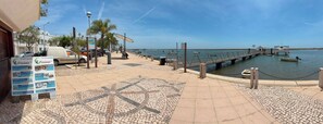 A coastal walkway with a mosaic pattern, a pier extending into the water, and parked cars along the side. - 3-Bedroom House in Santa Luzia, Near the Ria Formosa (Santa Luzia)