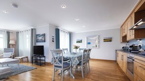 Une cuisine moderne avec des meubles en bois, un coin repas comprenant une table et des chaises, et un téléviseur.