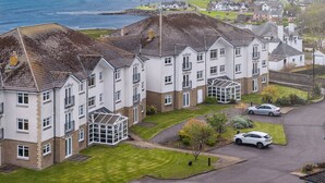 Un immeuble résidentiel doté de nombreux balcons, d’une pelouse bien entretenue et offrant une vue sur la mer.