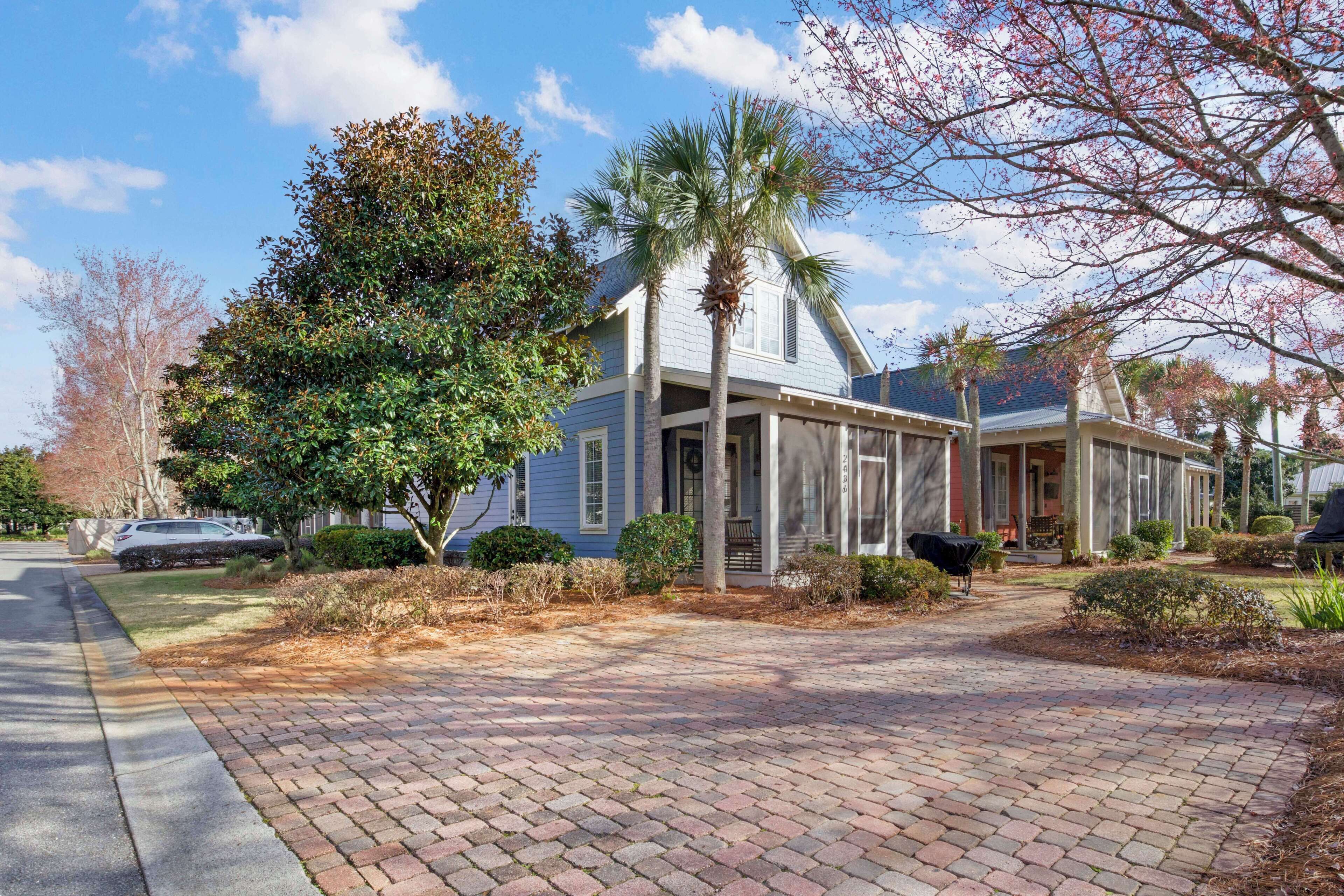 A two-story house with a covered porch, a driveway, and a lawn.