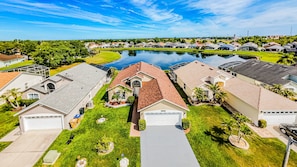 A residential area with houses, a swimming pool, and a clear sky. - Lake Serenity Retreat Private Pool, Lake Views, Game Room & Outdoor TV (Kissimmee)