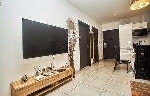 Ein modernes Wohnzimmer mit Flachbildfernseher, einem Holzkonsole, einer Vase mit Blumen, einem Spiegel und einem Essbereich mit Stuhl und Tisch.