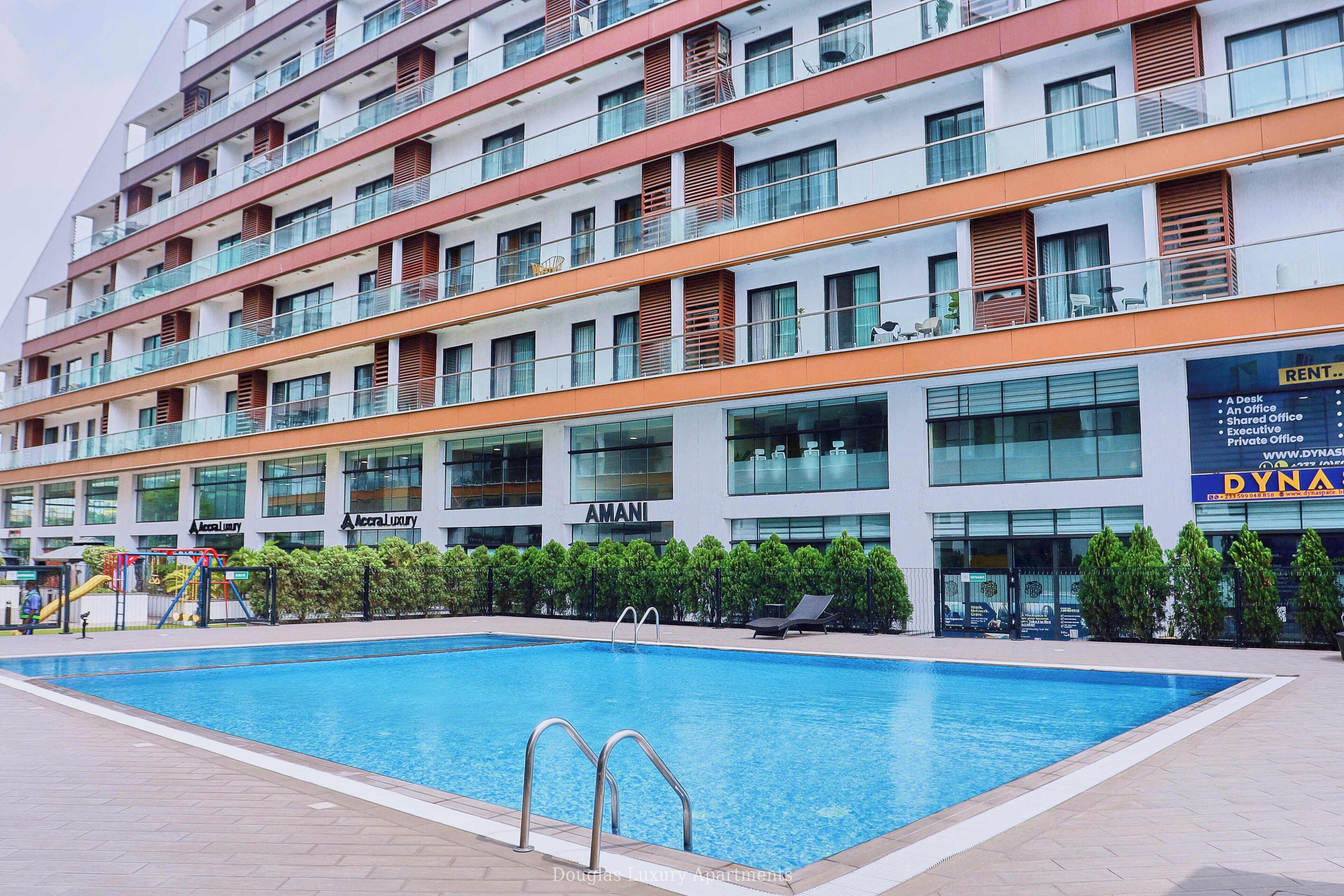 Un hotel moderno con piscina, varios balcones y un cartel que dice 'Dynasty' a la derecha.