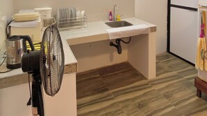 Eine Küche mit Spüle, Fenster, Ventilator und Holzboden.