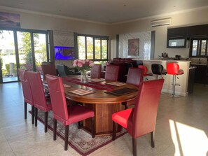 A dining area with a round table, red chairs, and a vase of flowers. - Pecanwood Picturesque Peaceful (Hartbeespoort)