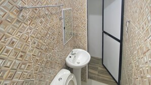 A bathroom with a toilet, sink, and shower area, featuring geometric patterned tiles and a white ceiling. - Simple, Practical & Comfy Room 4 (General Luna)