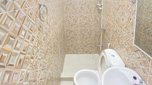 A bathroom with patterned tile walls, a toilet, a sink, and a shower. - Simple, Practical & Comfy Room 4 (General Luna)