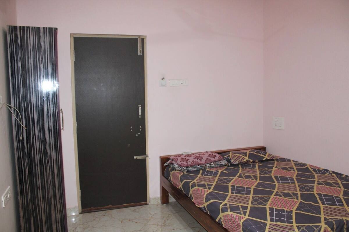 A bedroom with a bed, a door, and a wall socket.