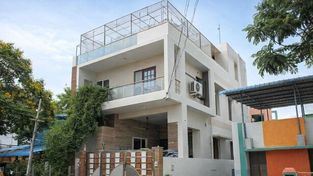 A multi-story residential building with a balcony, a gated entrance, and a covered porch. - S L Homestay (Tiruvannamalai)
