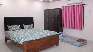 A bedroom with a bed, a wardrobe, an air conditioner, and a window with curtains. - S L Homestay (Tiruvannamalai)