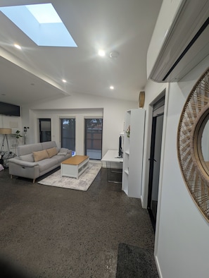 A modern living room with a sofa, coffee table, and a skylight.
