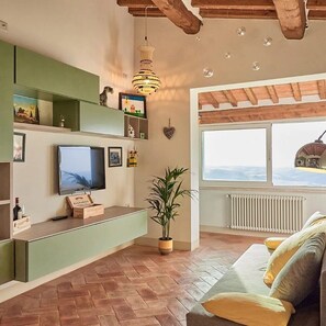 Un soggiorno con TV, mensole verdi, una pianta in vaso, un divano e vista dalla finestra.