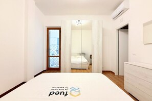 Ein Schlafzimmer mit Bett, Schrank, Spiegel und einer Tür, die auf einen Balkon führt.