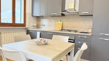 Una cocina moderna con armarios grises, encimera de madera y una mesa con sillas.