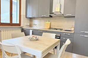 Una cocina moderna con armarios grises, encimera de madera y una mesa con sillas.