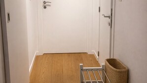 A hallway with a wooden floor, white walls, and a door at the end.