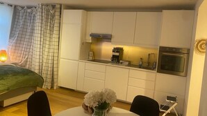 A compact kitchen with white cabinets, a coffee maker, and an oven.