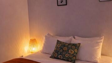 Ein Schlafzimmer mit einem Bett, einer Pendelleuchte und gerahmten Bildern an der Wand.