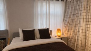 A neatly made bed with a dark brown cover, white pillows, and a bedside lamp.
