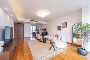Una sala de estar moderna con un sofá modular, un televisor de pantalla plana, una mesa de centro y una planta grande en maceta.