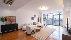 Una sala de estar moderna con un sofá modular, una mesa de centro redonda y un amplio ventanal con vistas a la ciudad.