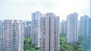 Edificios residenciales altos con múltiples balcones, rodeados de vegetación.