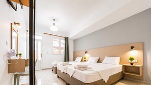 Una habitación de hotel con una cama grande, mesitas de noche, un escritorio con una silla, un espejo y una ventana con cortinas.