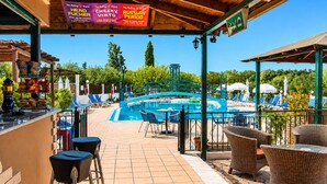 A poolside area with lounge chairs, a bar, and a sign advertising the Rolling Stones brand. - Nikos Villas - Poolside Escape in Kavos, Corfu (Corfu)