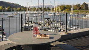 A table with a pitcher, glasses, and sunglasses, overlooking a marina with boats. - Mereside Apartment Ridgestone (Windermere)