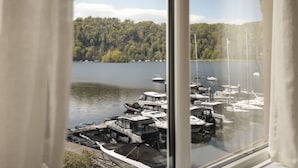 A marina with boats docked, surrounded by a forested area. - Mereside Apartment Ridgestone (Windermere)