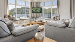 Ein modernes Wohnzimmer mit großem Fenster, Flachbildfernseher, Sofa, Couchtisch und einer Vase.