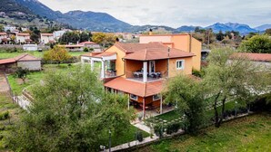 A two-story house with a balcony, surrounded by greenery and mountains. - Kalavrita Milodesi Country House Mountain Retreat (Kalavrita)