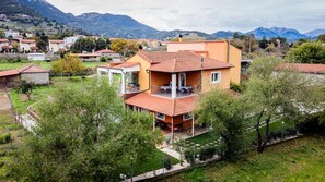 A two-story house with a balcony, surrounded by greenery and mountains. - Kalavrita Milodesi Country House Mountain Retreat (Kalavrita)