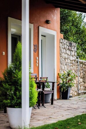 Un patio con mesa y sillas, un muro de piedra y plantas en macetas.