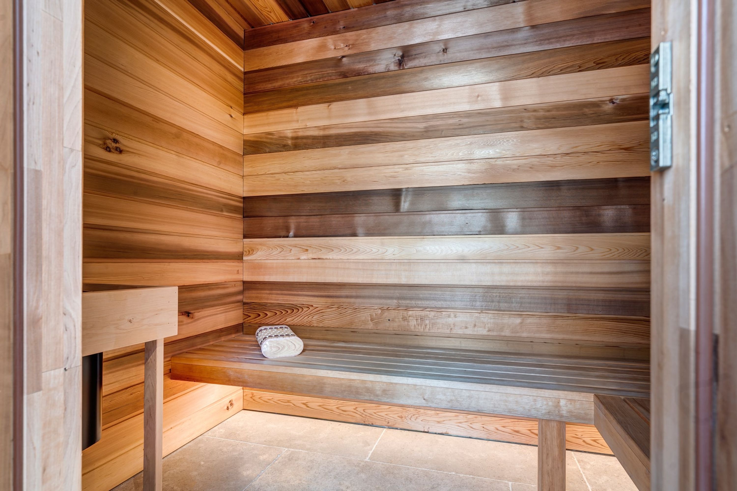 A wooden sauna with a bench and a towel on the floor.