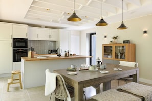 A modern kitchen with white cabinetry, a wooden island, and pendant lighting. - Fawns Keep - Hot Tub Sauna Retreat Ridgestone (Windermere)