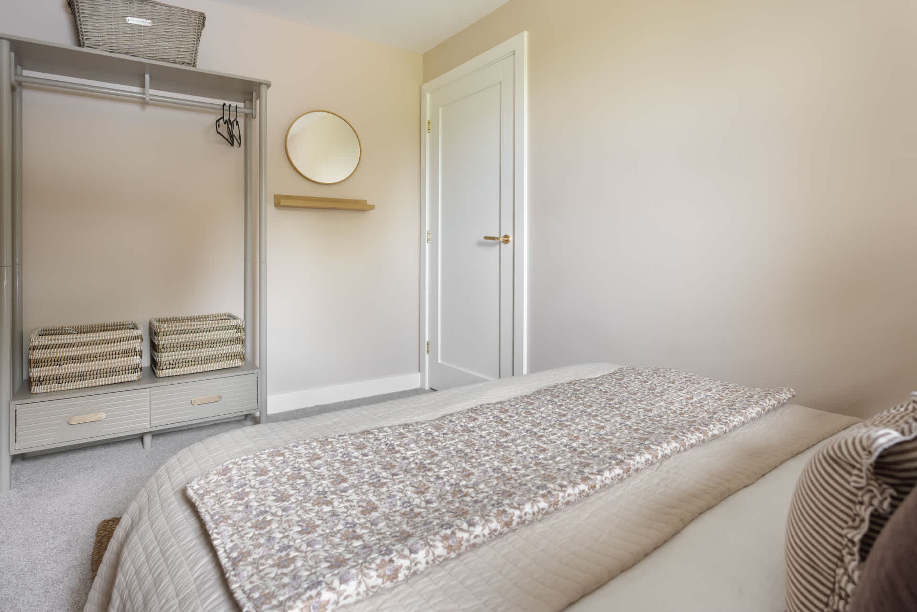 A bedroom with a bed, a wardrobe, a mirror, and a door.