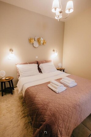 A bedroom with a large bed, two bedside tables, a chandelier, and wall sconces. - Kalavrita Milodesi Country House With Fireplace (Kalavrita)