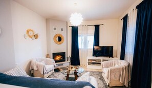A living room with a fireplace, two sofas, a coffee table, and a TV on a stand. - Kalavrita Milodesi Country House With Fireplace (Kalavrita)