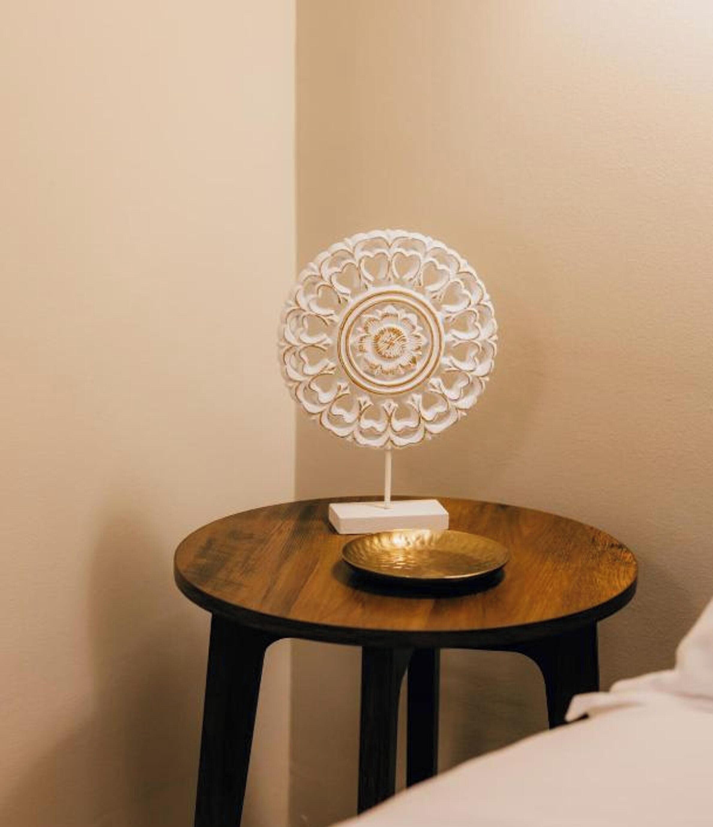A small round wooden table with a white decorative stand and a white box on top.