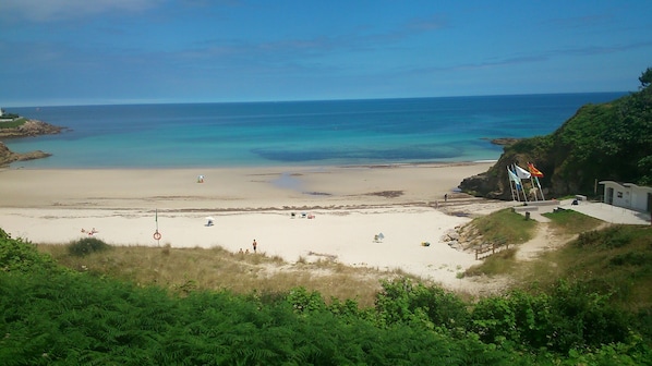 Uma praia com águas azuis cristalinas, uma torre de salva-vidas e uma bandeira.